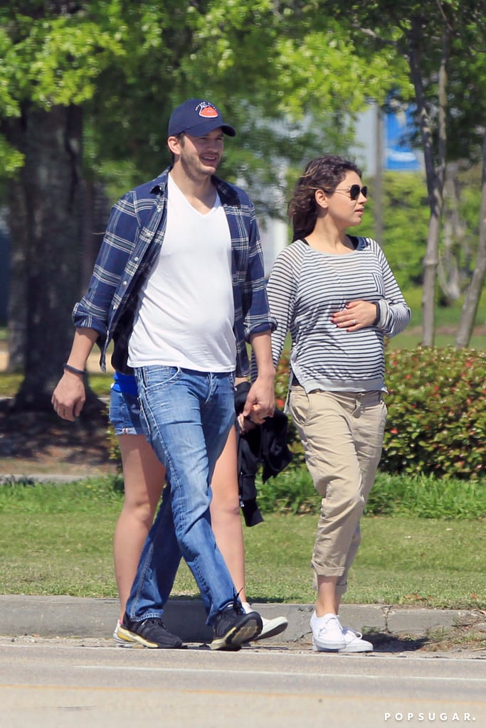 Mila Kunis Shows Baby Bump at Airport With Ashton Kutcher