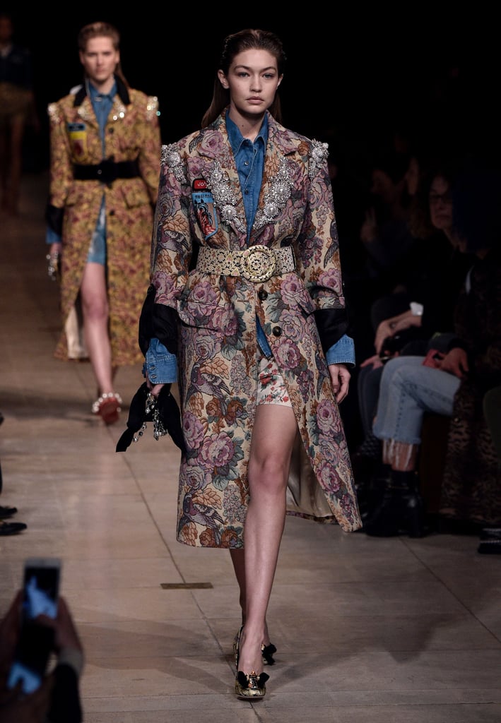 Gigi's last Fall '16 catwalk appearance was at Miu Miu, where she covered a denim button-up in a jacquard floral coat and contrast belt, letting her silk shorts peek out from underneath. Gigi's look came accessorized with bow-finished pumps and a dainty purse.