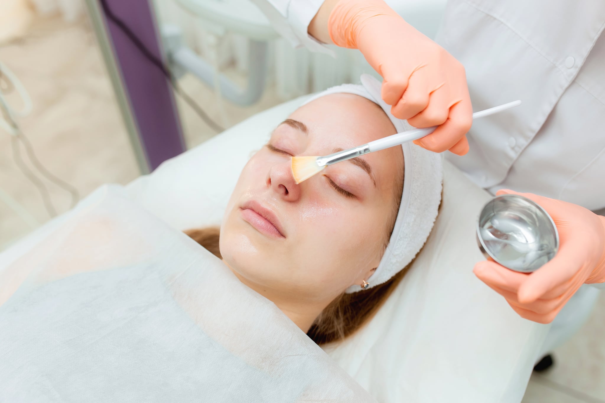 Cosmetologist applying mask on client's face in spa salon. Wellness center. Healthcare occupation