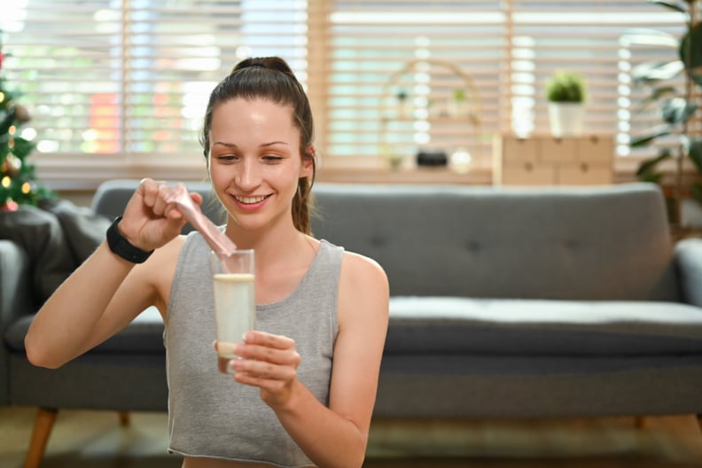 Woman dissolving collagen powder in a glass of water.