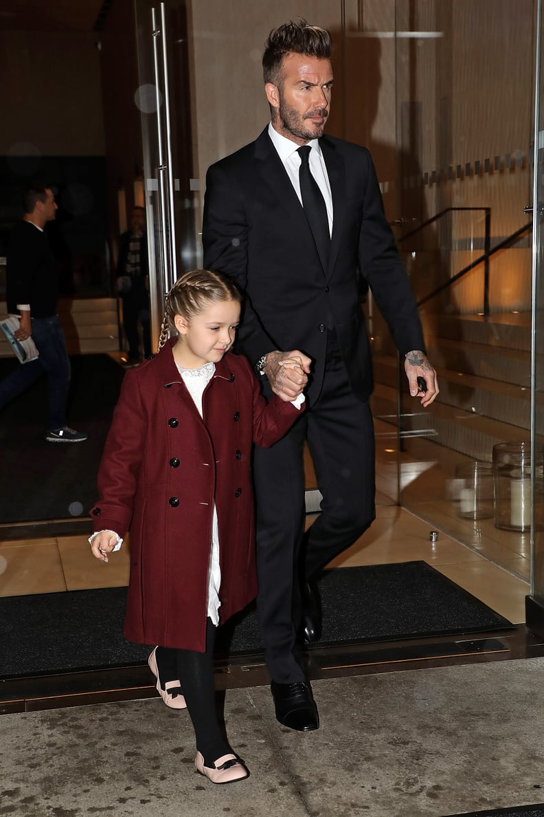 David Wore a Black Suit and Held on to Harper's Hand, Who Wore a Burgundy Coat Over a White Dress and a Pair of Black Tights