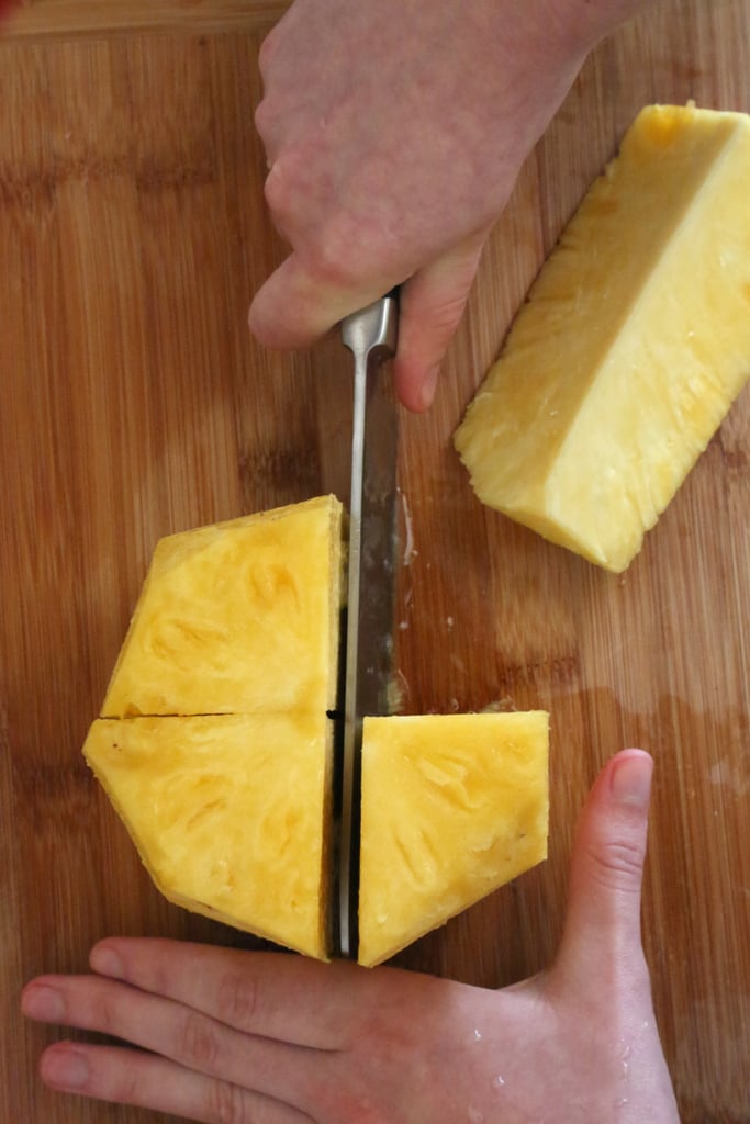 Rotate the knife 90 degrees and cut through the center again, resulting in four even pineapple pieces.