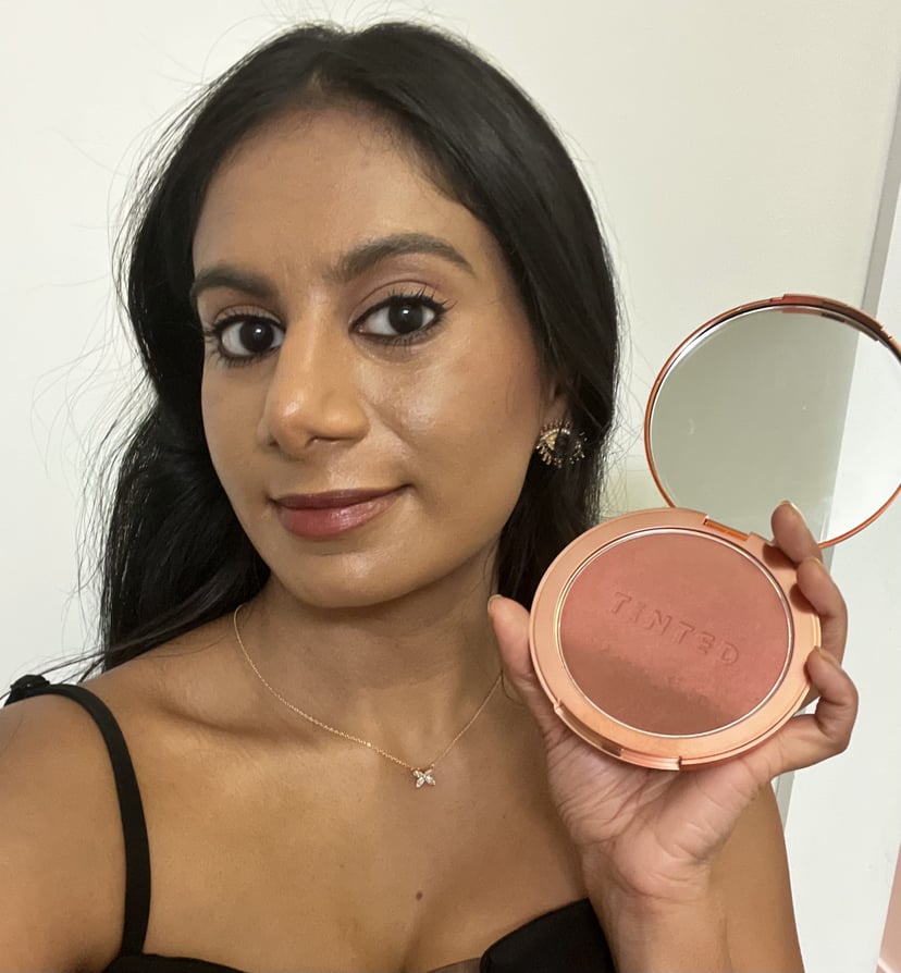 Woman holding the Live Tinted Huebeam Blushing Bronzer.