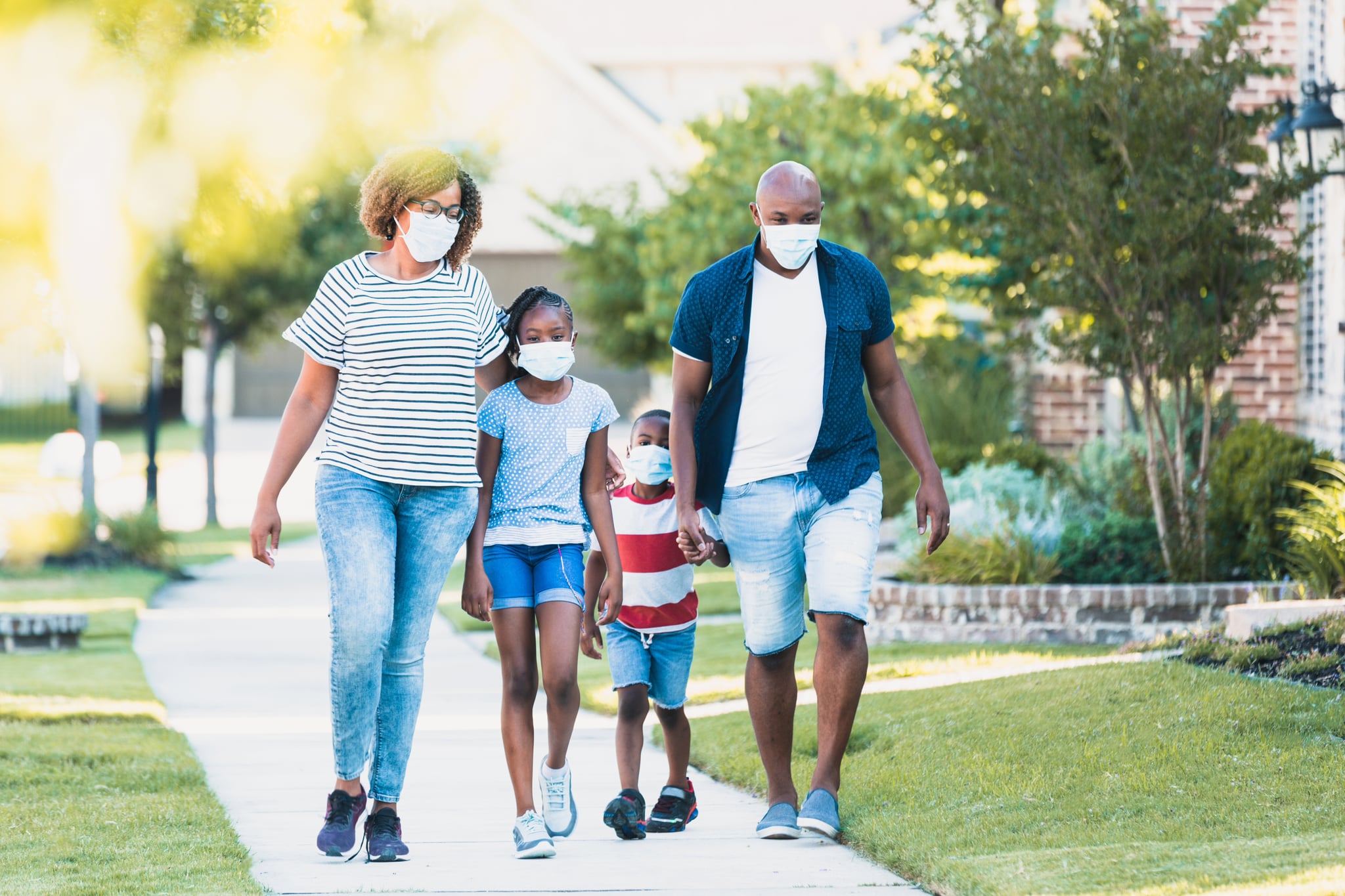 A happy family wear face masks while walking in their neighbourhood during the COVID-19 pandemic.