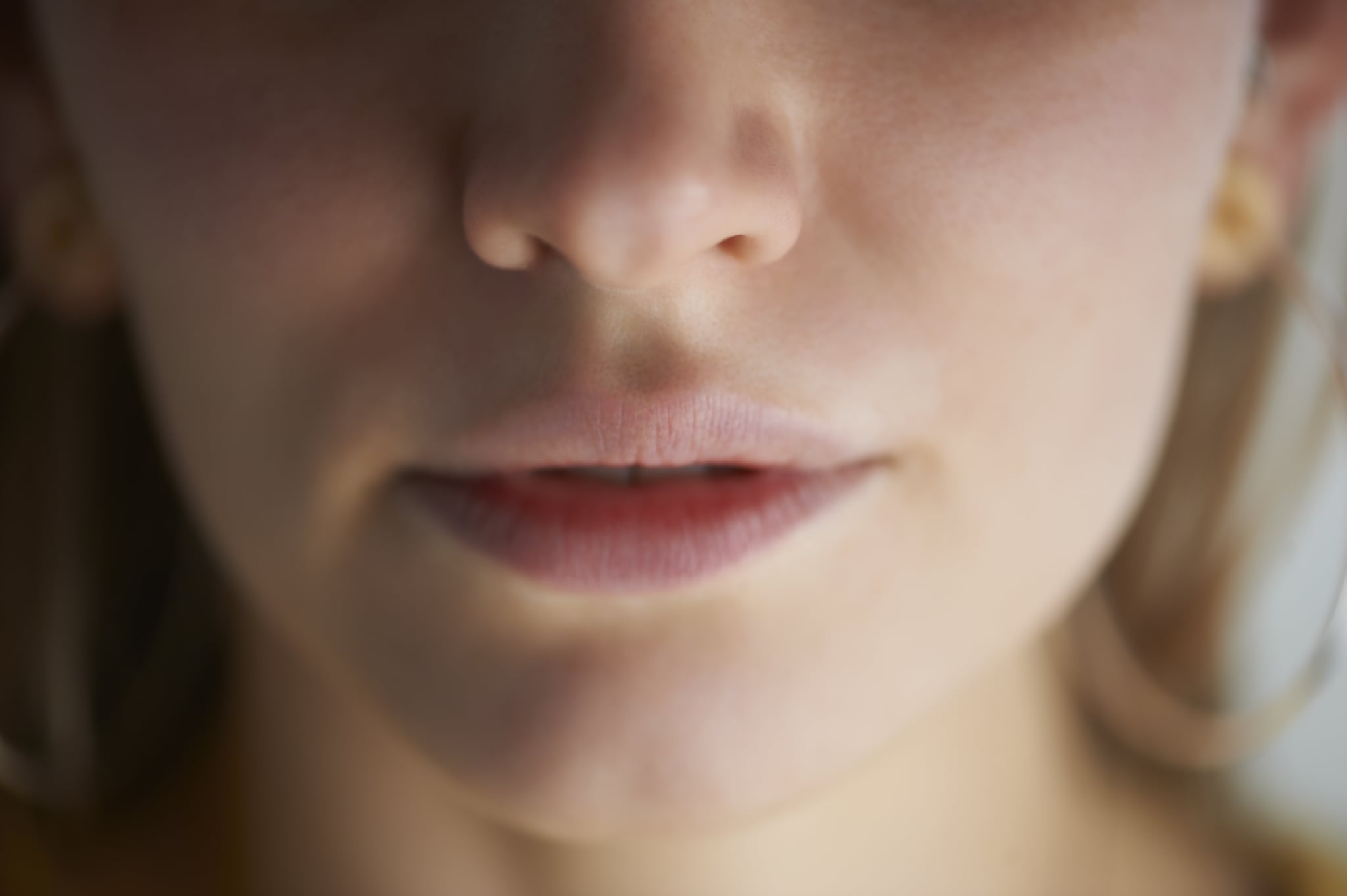 Female face close up focussed on mouth and nose in daylight studio.