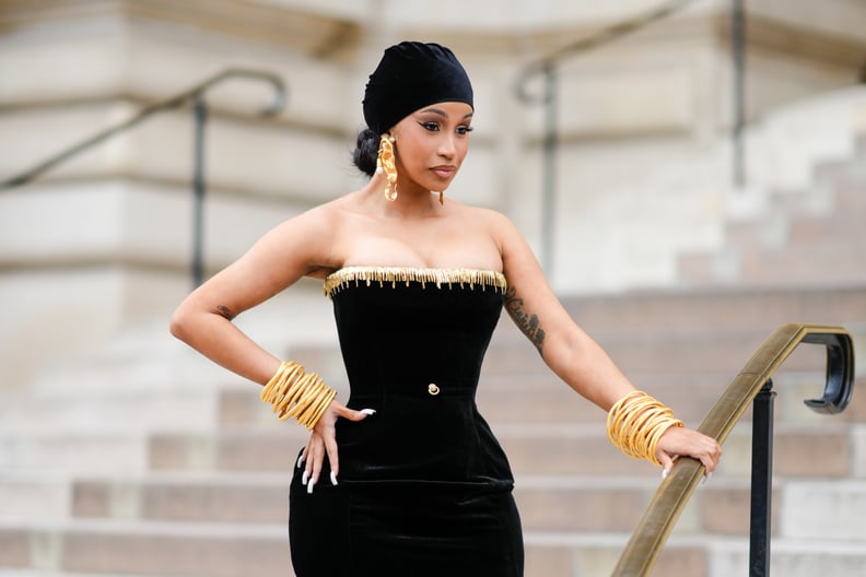 PARIS, FRANCE - JULY 03: Cardi B wears a black velvet scarf as a hat from Schiaparelli, gold large ears and white pearls pendant earrings from Schiaparelli, a black velvet with embroidered gold metallic shoulder-off borders / long tube dress from Schiapar
