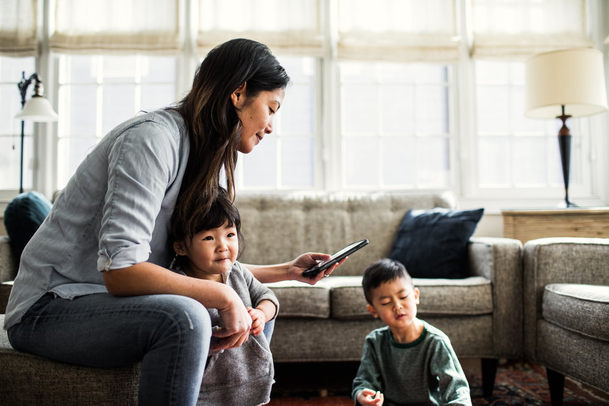 Mother using smartphone with children present