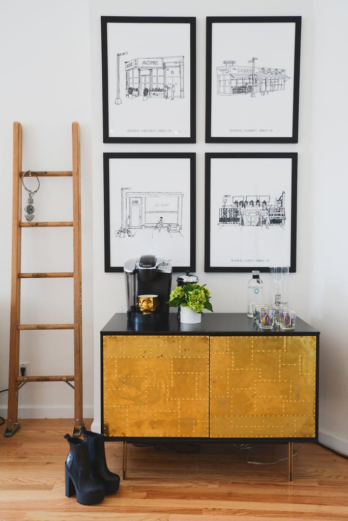 Man Repeller's beverage station does double-duty as a morning-coffee and evening-cocktail bar. A quartet of local coffee shop prints hanging above continue the java theme while personalizing the space. Beyond the drinking accoutrements, the console is bare but for a Jonathan Adler Gold Muse Candle, and a wooden ladder serves as a magazine or jewelry rack just to the side. 
Photo by Claire Esparros via Style Me Pretty