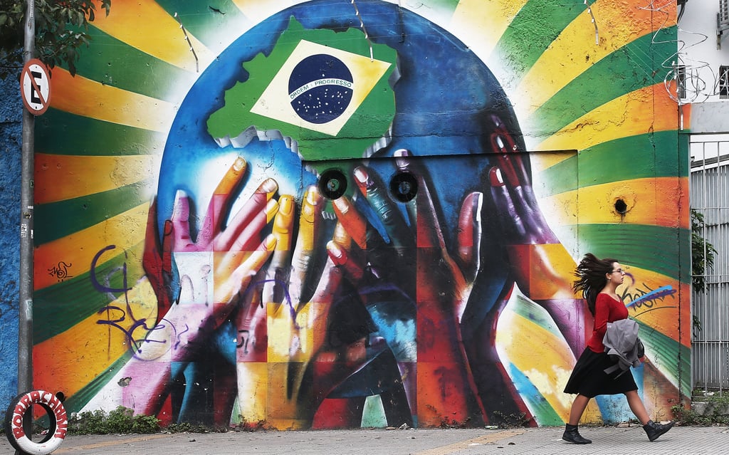 A woman walked past the colorful graffiti wall marked with a Brazilian flag in São Paulo.