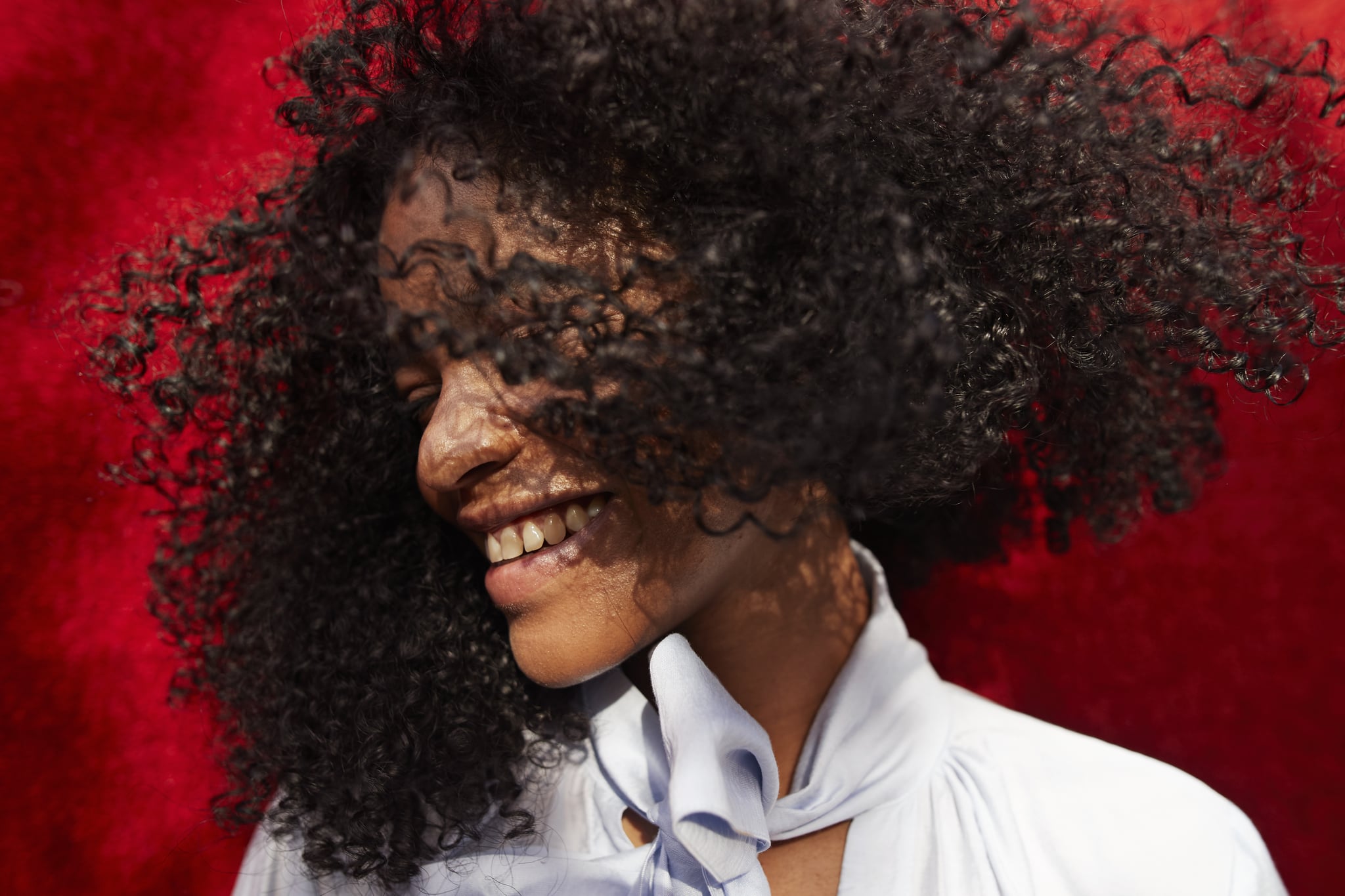 Close-up of smiling young woman against red wall