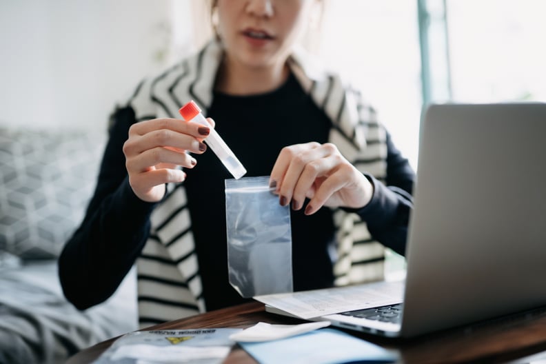 Cropped shot of young Asian woman consulting to her family doctor online in a virtual appointment, holding a medical test tube, conducting Covid-19 diagnostic test at home