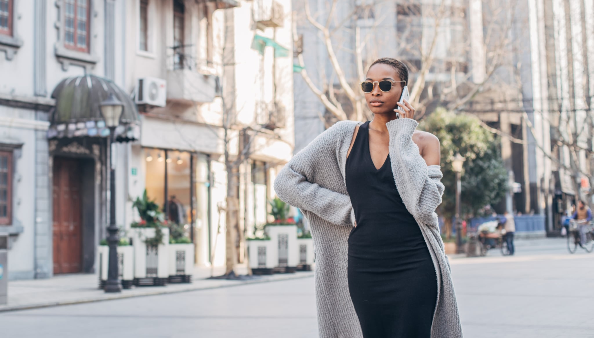 One woman, standing on street downtown, using mobile phone.