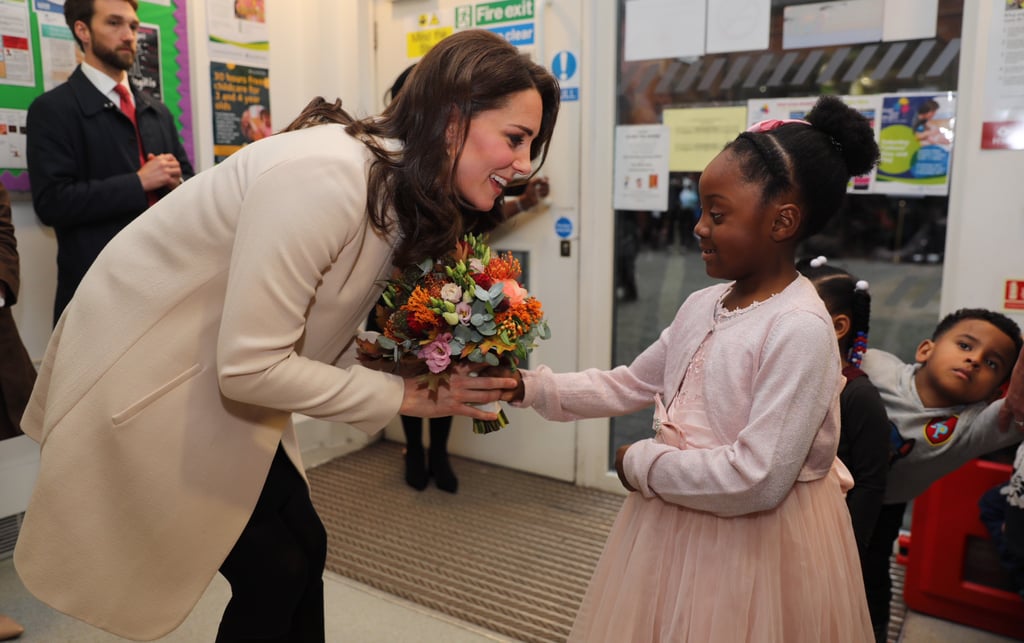 Kate Middleton visited the Hornsey Road Children's Center in London, but she gave us only the tiniest peek at her growing belly. Covering up in a chic cream coat that she first debuted when she was pregnant with Prince George, Kate, who is currently expecting her third child, met with children before hearing some of the personal experiences from parents who have benefited from the charity, which provides childcare, family support, and outreach services in the local area.
It's been a busy time for the duchess, who is back to her royal duties after suffering from hyperemesis gravidarum in the early stages of her third pregnancy. We last saw her at the Remembrance Sunday service on Nov. 12. A few weeks ago, Kate revealed that she was now feeling well enough to drop her son off at Thomas's Battersea School, and she recently stunned everyone in a gorgeous lace-sleeved dress at a gala dinner for the Anna Freud National Center for Children and Families.