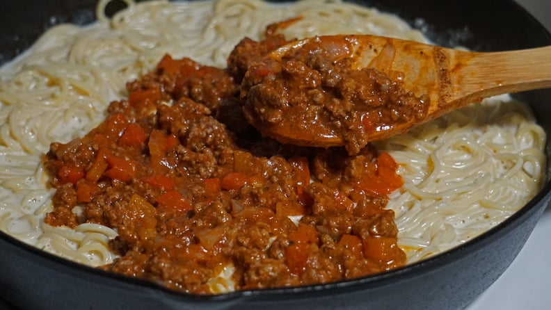 million dollar spaghetti recipe: pouring bolognese over pasta