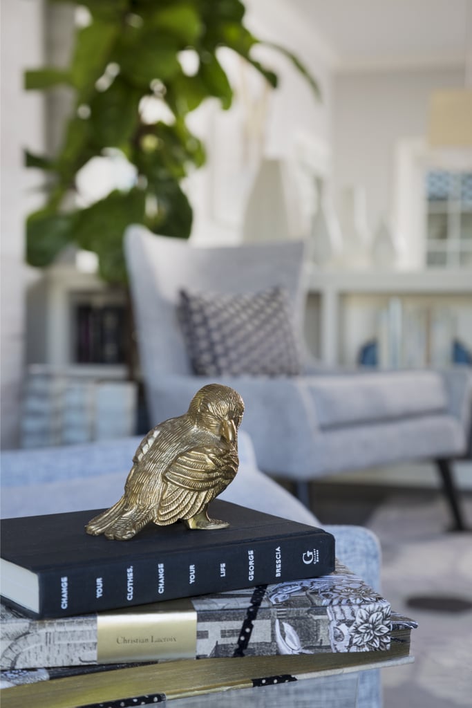 A gold bird sits atop a stack of books in the living room.