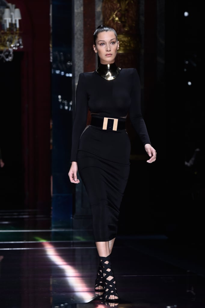 While Gigi sported natural colors, Bella went all-black in a belted formfitting midi that boasted sheer panels. Her outfit was complete with a thick metal choker, wide geometric belt, and strappy heels.