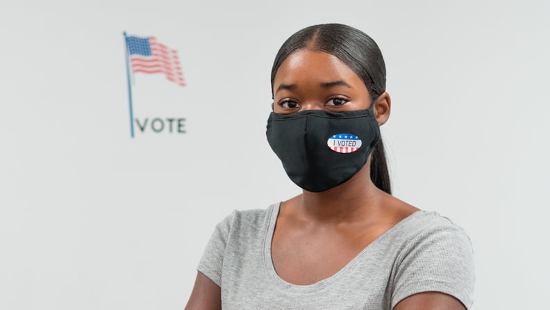 Proud young woman poses by the American flag at w voting station.