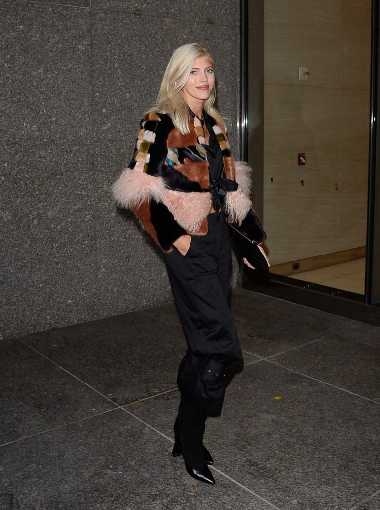 Devon Windsor wearing a patchwork jacket with black pants and ankle boots.