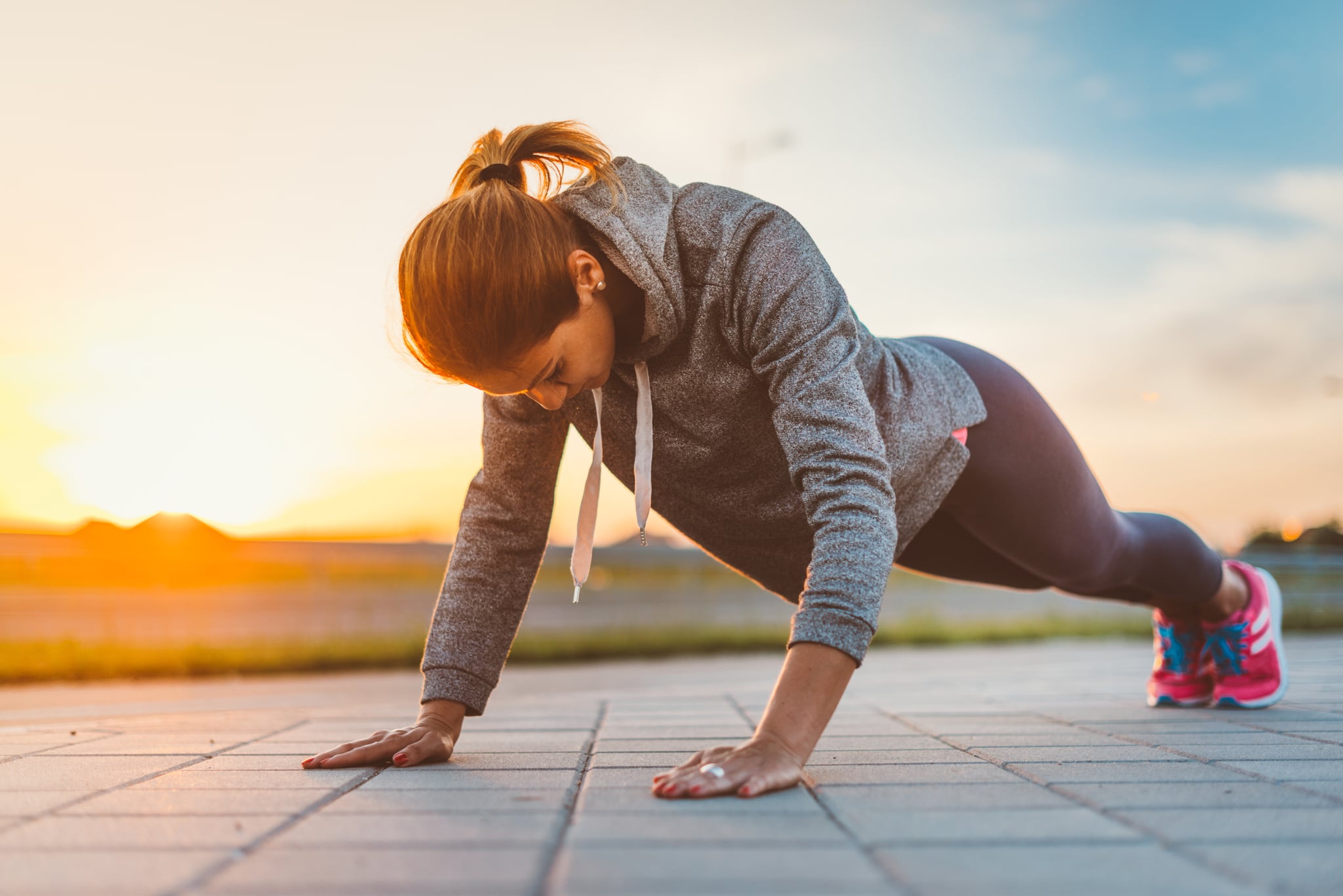 Image of young woman in good physical shape and form, doing push ups in summer sunset, in Novi Sad, Serbia, Europe