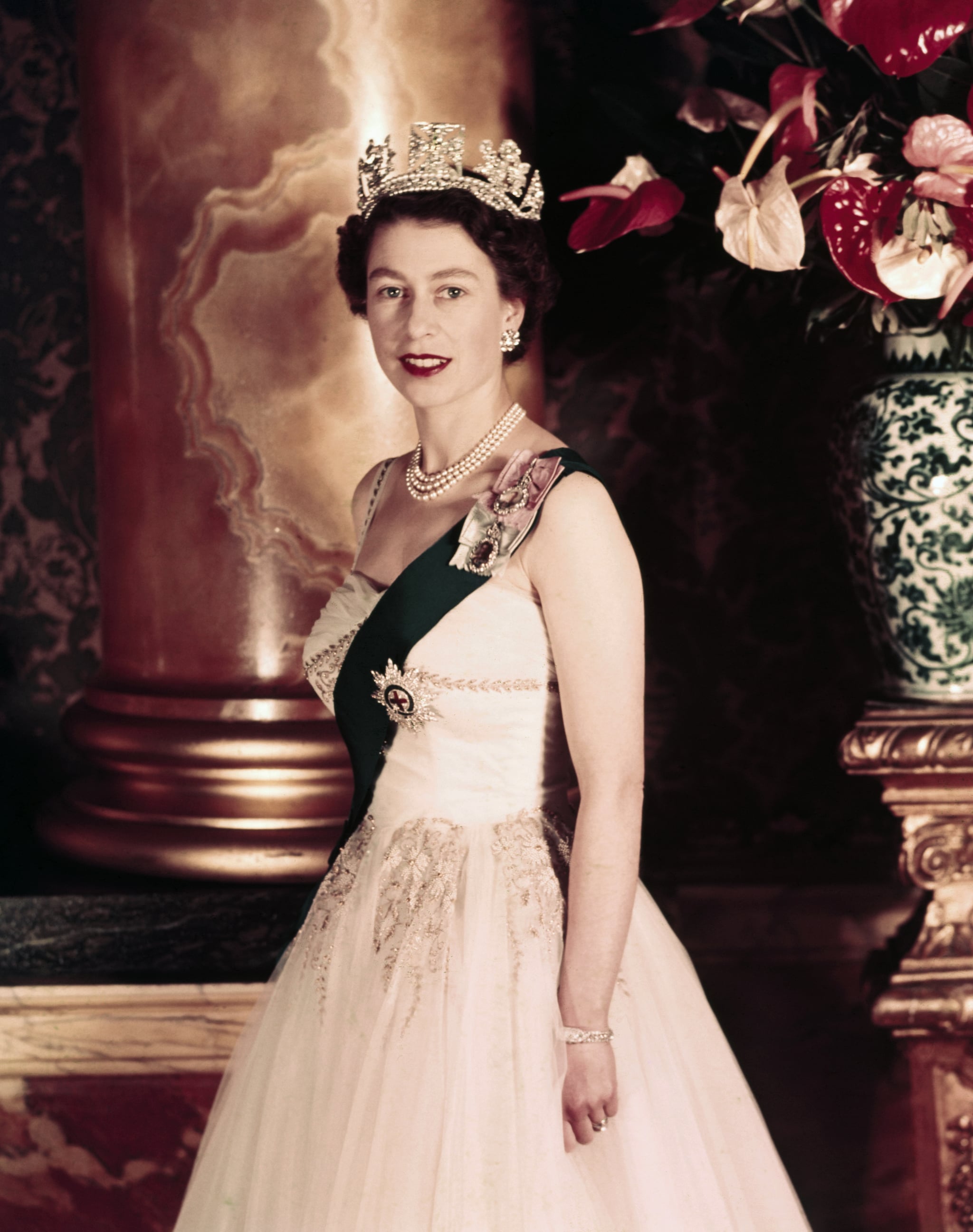 Queen Elizabeth II poses wearing a formal sash and crown in 1955