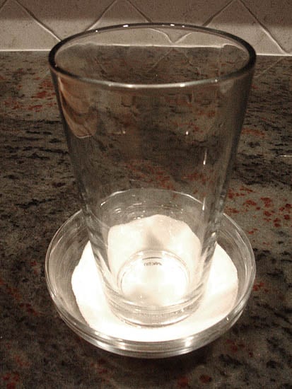 Dipping the bottom of a glass in sugar to prevent sticking to the cookie dough balls. Dipping the bottom of a glass in sugar to prevent sticking to the cookie dough balls.