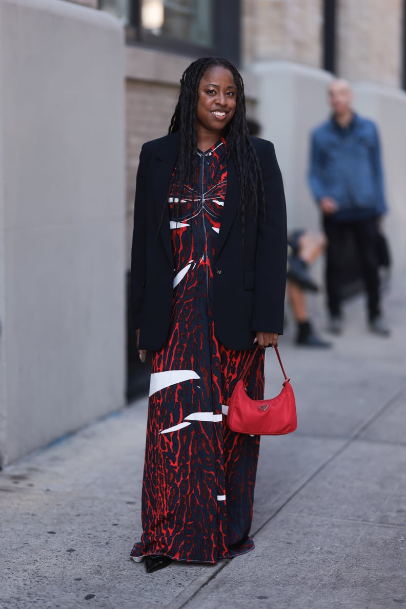 NEW YORK, NEW YORK - SEPTEMBER 12: Guest is seen outside Brandon Maxwell show wearing navy blue blazer, white, red and blue patterned dress, black Prada nylon hobo handbag and black leather heels on September 12, 2023 in New York City. (Photo by Jeremy Mo