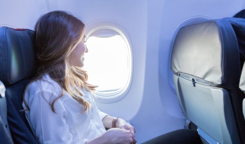 在这边看来,一个微笑的年轻女人喜欢看着窗外的飞机,她等待到达她的目的地。