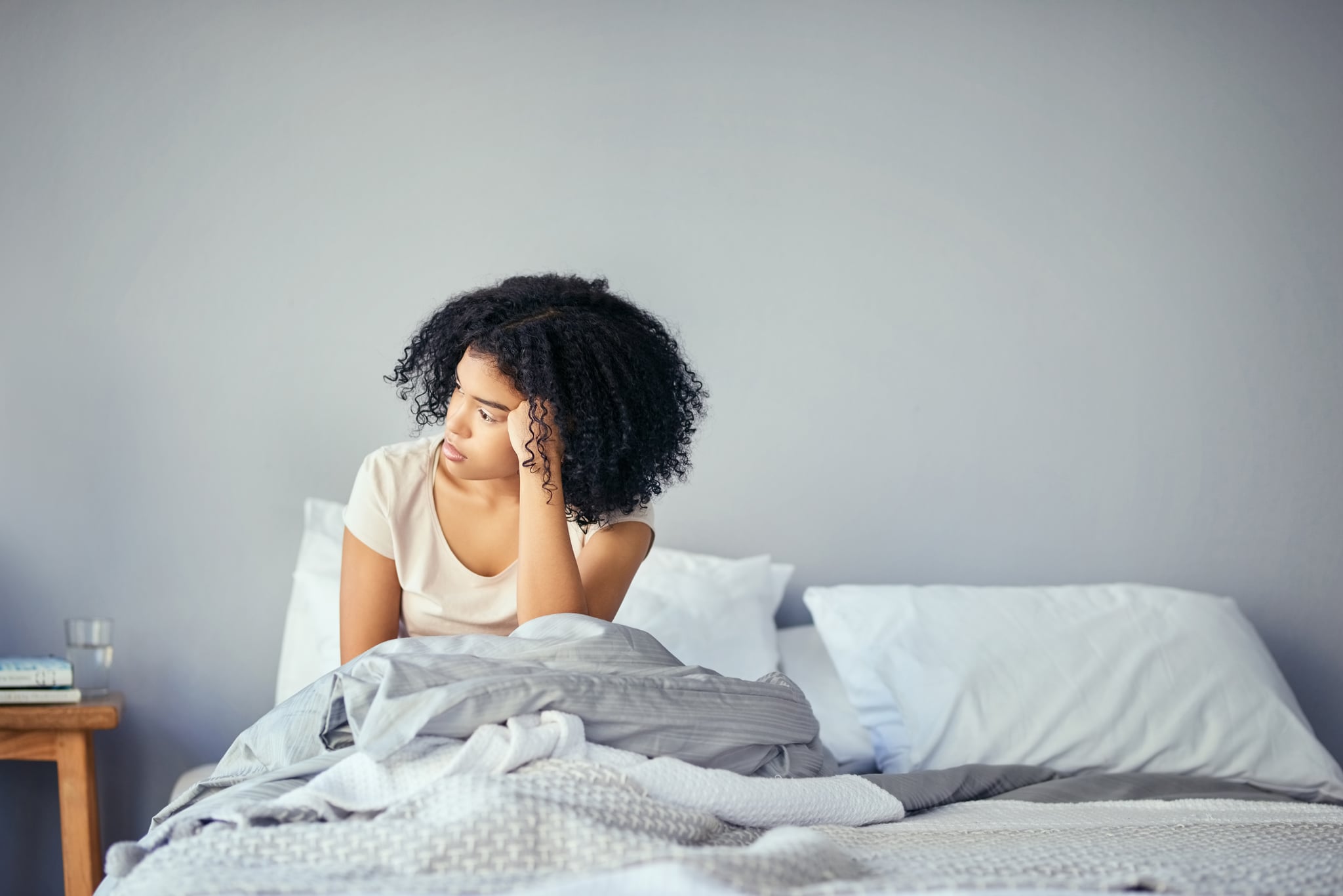 Shot of a young woman suffering from depression in her bedroom