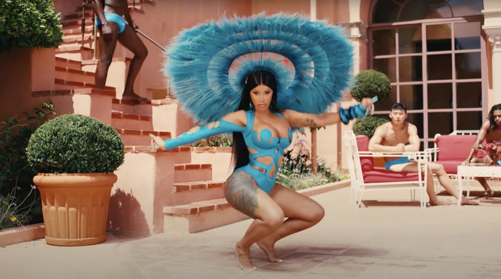 In the following scene, she changes into a blue Matthew Reisman one-piece with intricate cutout details and a matching feathered headpiece by Harris Reed. She ditches the heels to drop it low.
