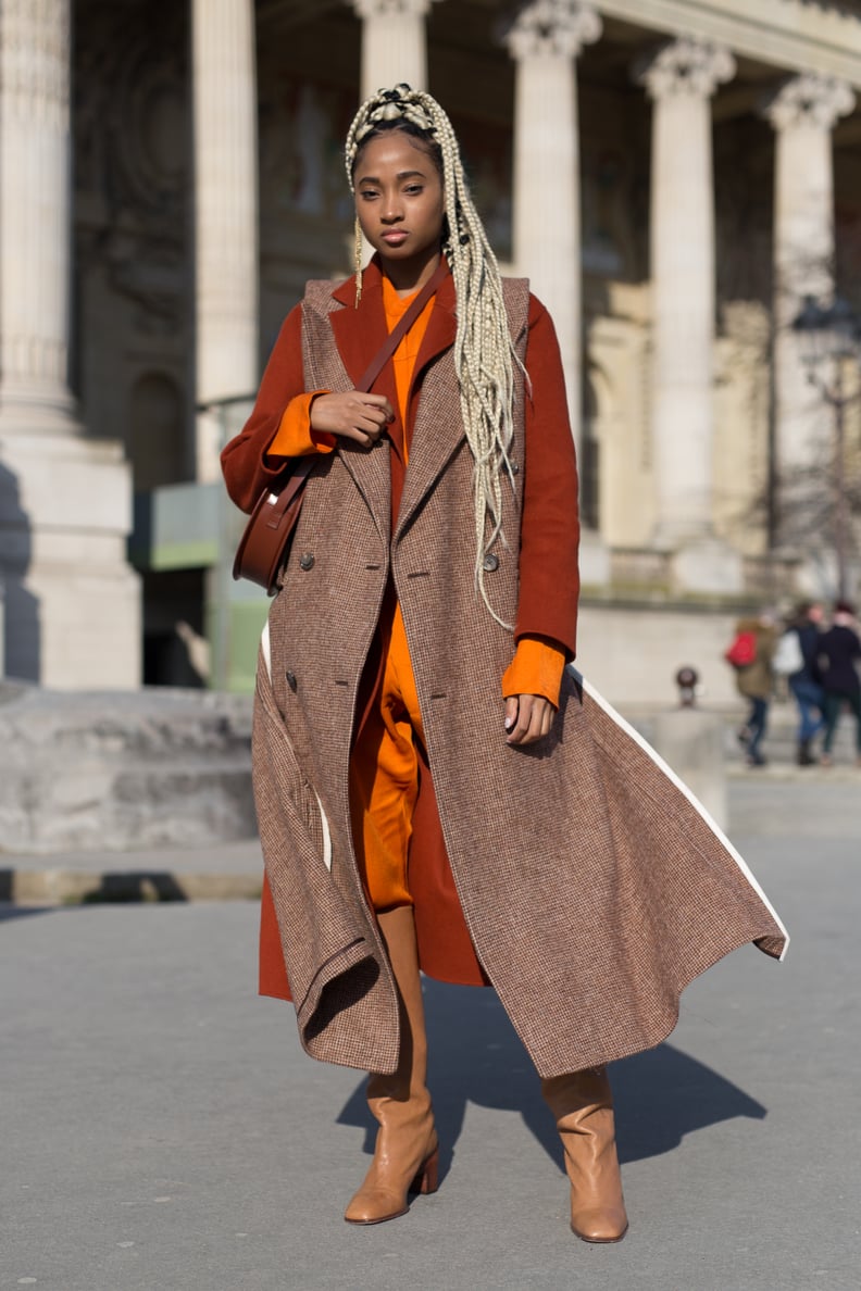 A Bright Orange Jumpsuit, Rust Coat, Brown Sleeveless Jacket, and Boots