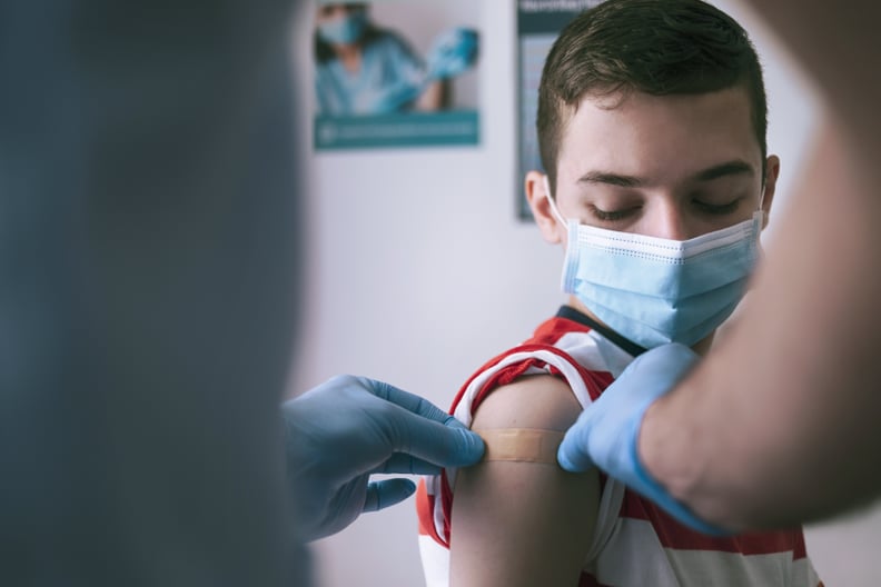 Doctor putting adhesive bandage to a teenage boy after Covid-19 vaccine injection.