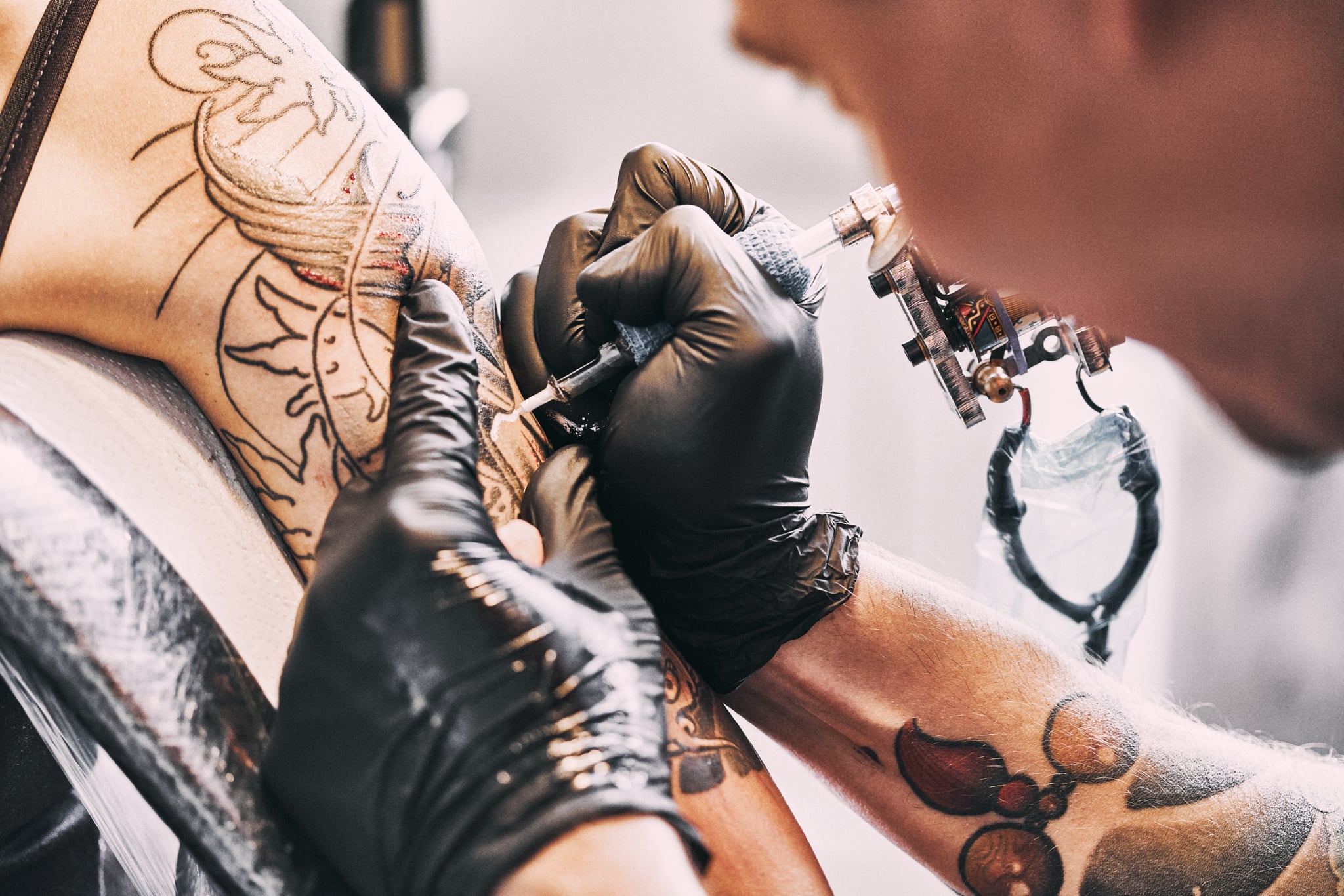 Tattoo Artist making a tattoo on a shoulder in tattoo studio