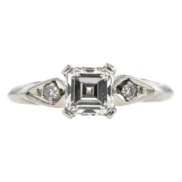 "This vintage Asscher cut diamond ring contrasts the straight step cuts of the centre with the round side stones. The kite-shaped frames play off the geometry of the centre stone to enhance the overall design."