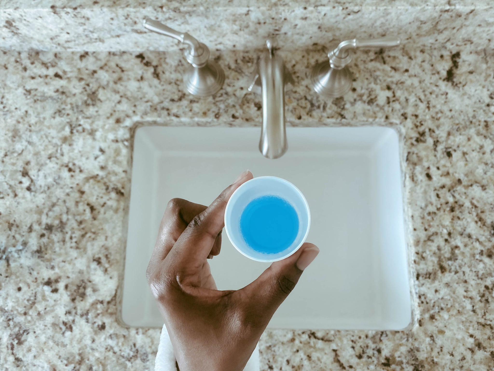 Close-up of woman's hand holding cup of mouthwash