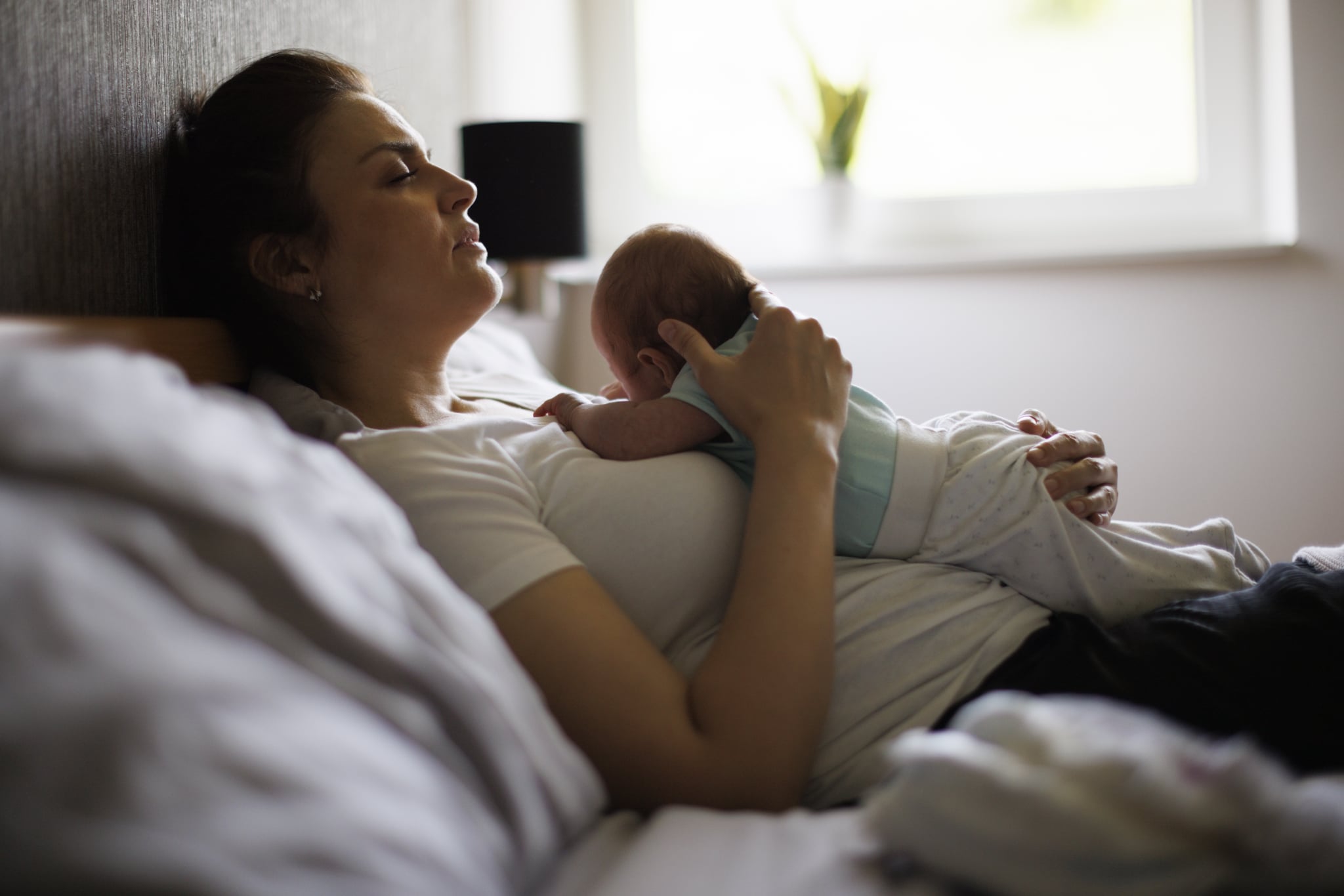 Exhausted mother holding her crying newborn baby. 
