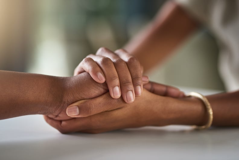 Cropped shot of two unrecognizable businesswomen holding hands in comfort while sitting in their office