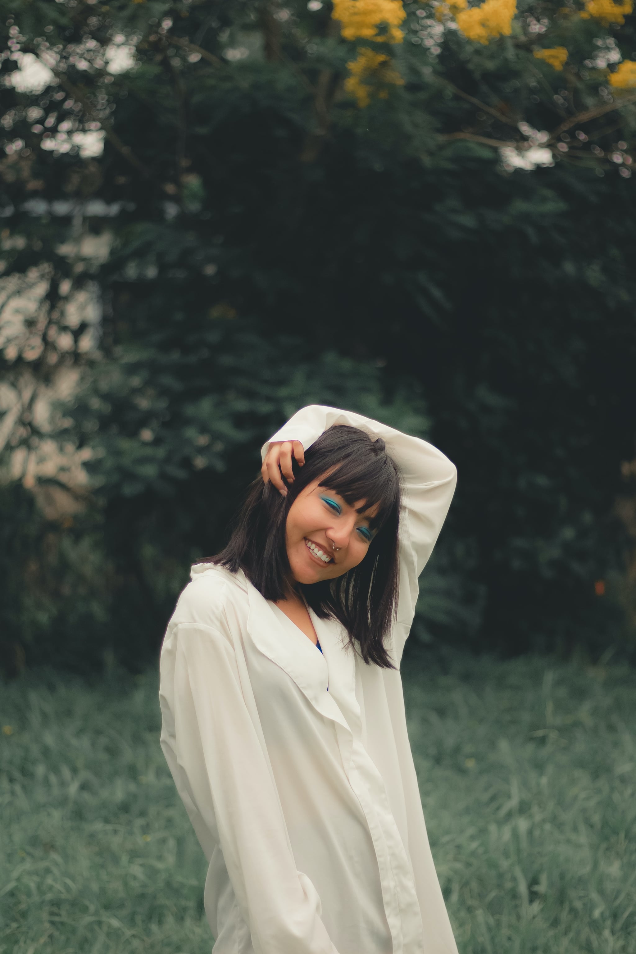 Woman with blue eyeliner and bangs in field to represent rising sign in astrology