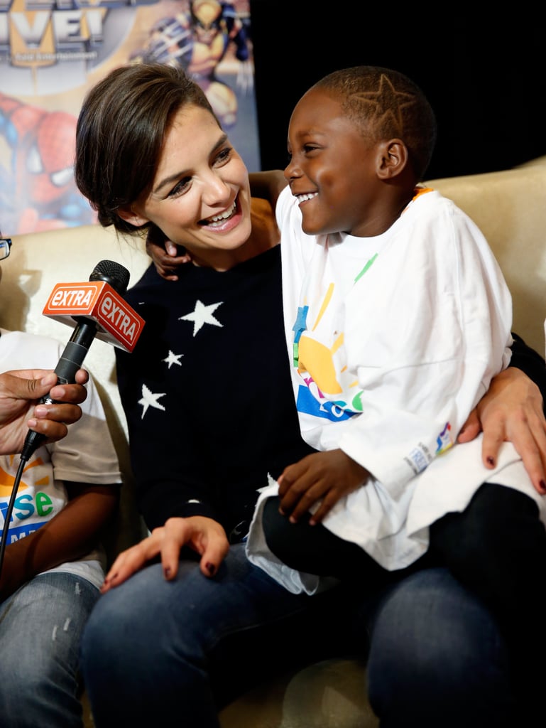 On Wednesday, Katie Holmes couldn't help smile while holding a sweet kid at the Marvel Universe Live! premiere in NYC, where children with cancer from Sunrise Day Camp got some one-on-one time with the star.