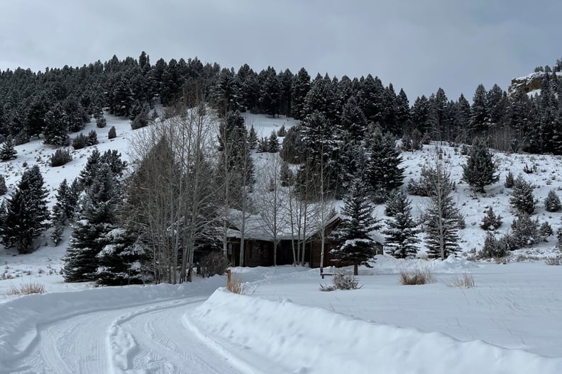 A view of the Sara Jane cottage at Montana's 5-star Ranch at Rock Creek, which I thought might be haunted. A luxury log cabin in the snow, set against pine-dotted hills.