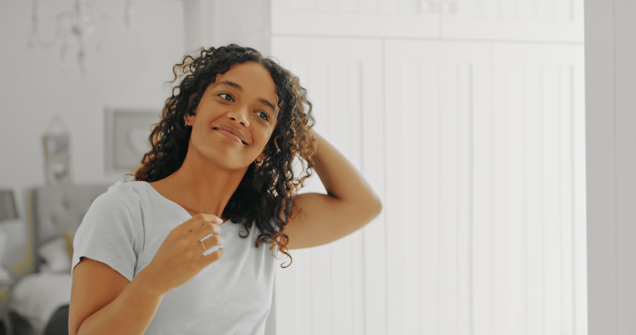 Cropped shot of an attractive young woman styling her hair in her bathroom at home