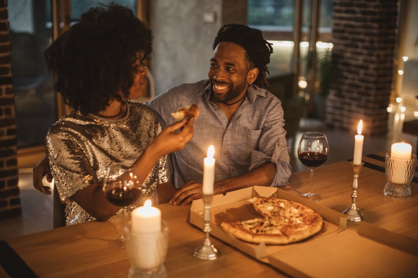 Young couple having romantic dinner at home. Eating pizza and drinking wine. Well dressed.