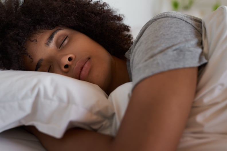 Close-up of a young African woman lying fast asleep in her comfortable bed at home in the morning