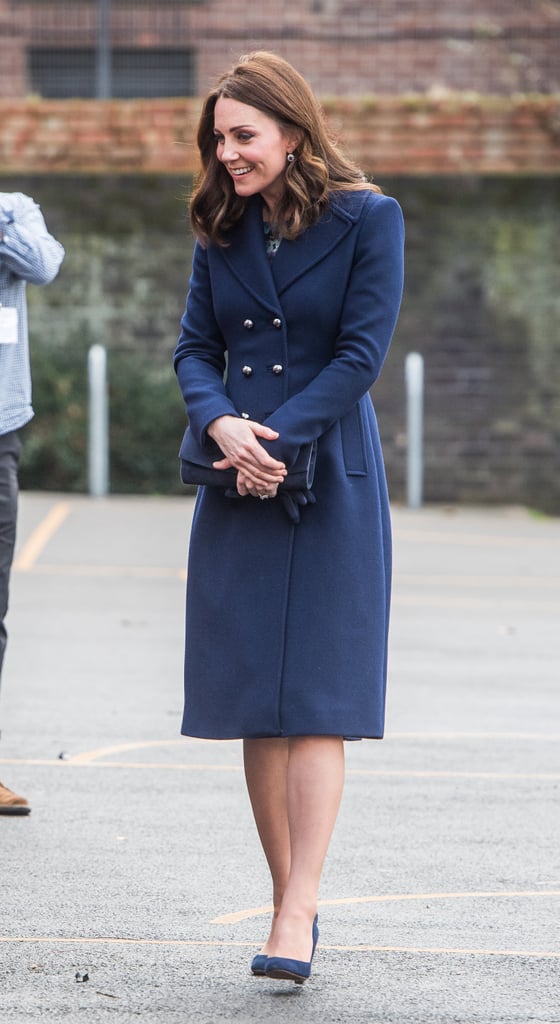 For her visit to the Reach Academy with Place2Be, the duchess chose to wear a long navy Hobbs coat with matching indigo gloves, a clutch, and a pair of suede Jimmy Choo pumps.