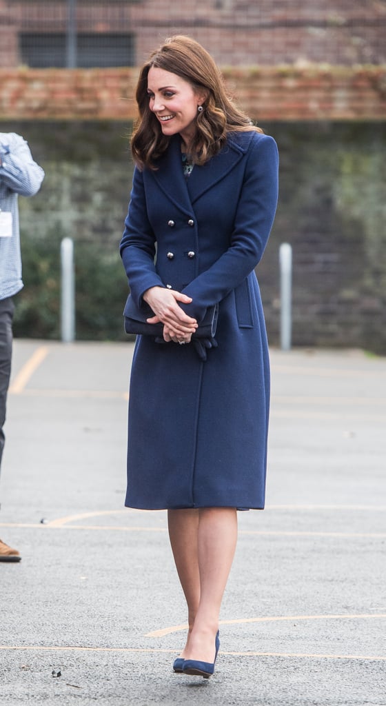For her visit to the Reach Academy with Place2Be, the duchess wore a long navy Hobbs coat with matching indigo gloves, a clutch, and a pair of suede Jimmy Choo pumps.