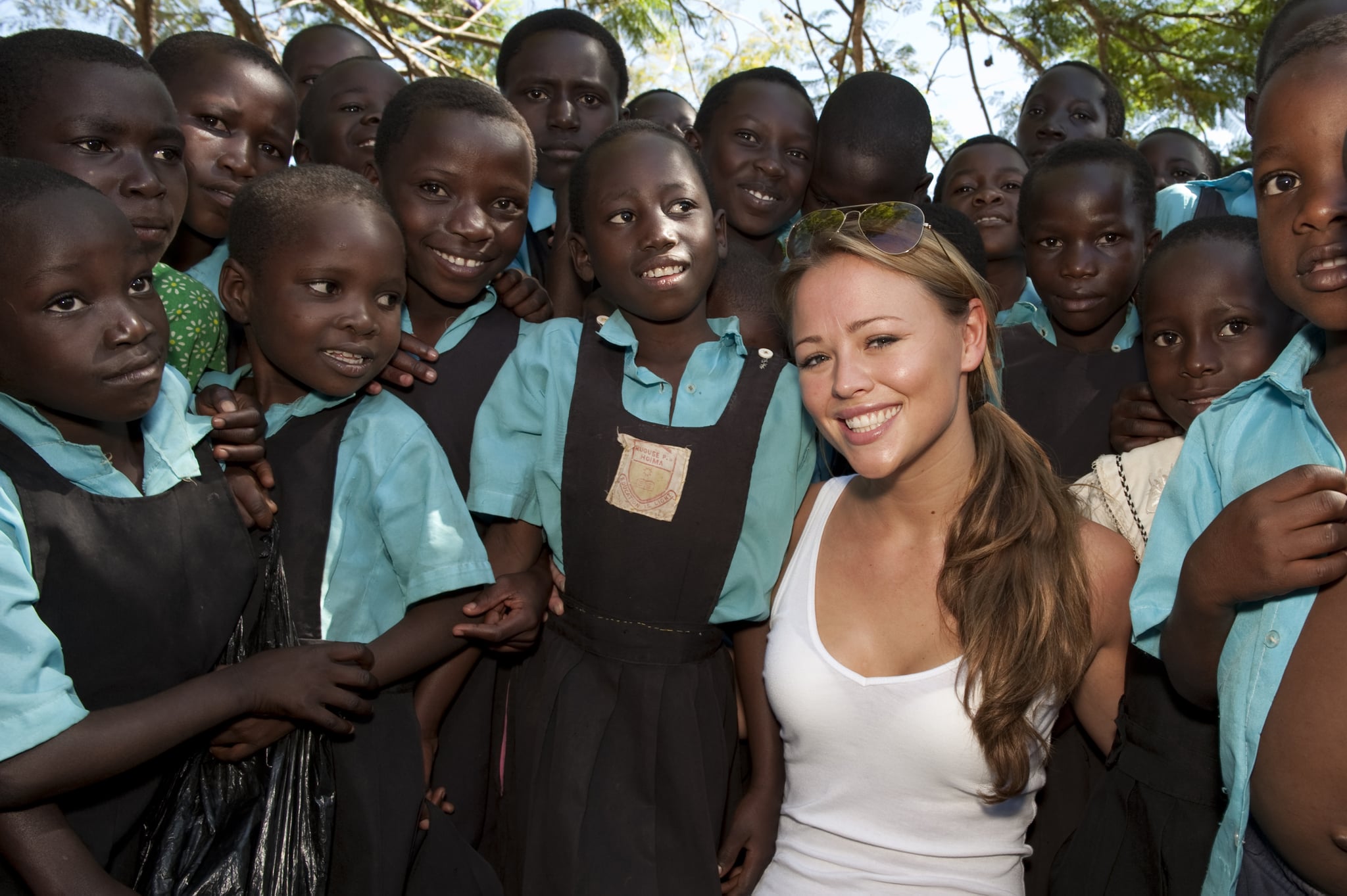 HOIMA, UGANDA - NOVEMBER 29: Kimberley Walsh poses with school local children as she visits a School where she is helping to hand out moquito nets on November 29, 2009 in Hoima, Uganda. Five of the nine celebrity Kilimanjaro climbers, Gary Barlow, Fearne Cotton, Ben Shepherd, Chris Moyles and Kimberley Walsh, saw all their hard work climbing the mighty Mount Kilimanjaro pay off as they witnessed for themselves how some of the money raised is being spent to help to fight malaria, Africa's biggest killer. The team are revisiting Africa to see how the money raised over Red Nose Day is being spent, as well as helping to hand out malaria nets. You can see how the team got on by watching BBC One 6.30pm Sunday 27th December.  (Photo by Des Willie/Comic Relief via Getty Images)