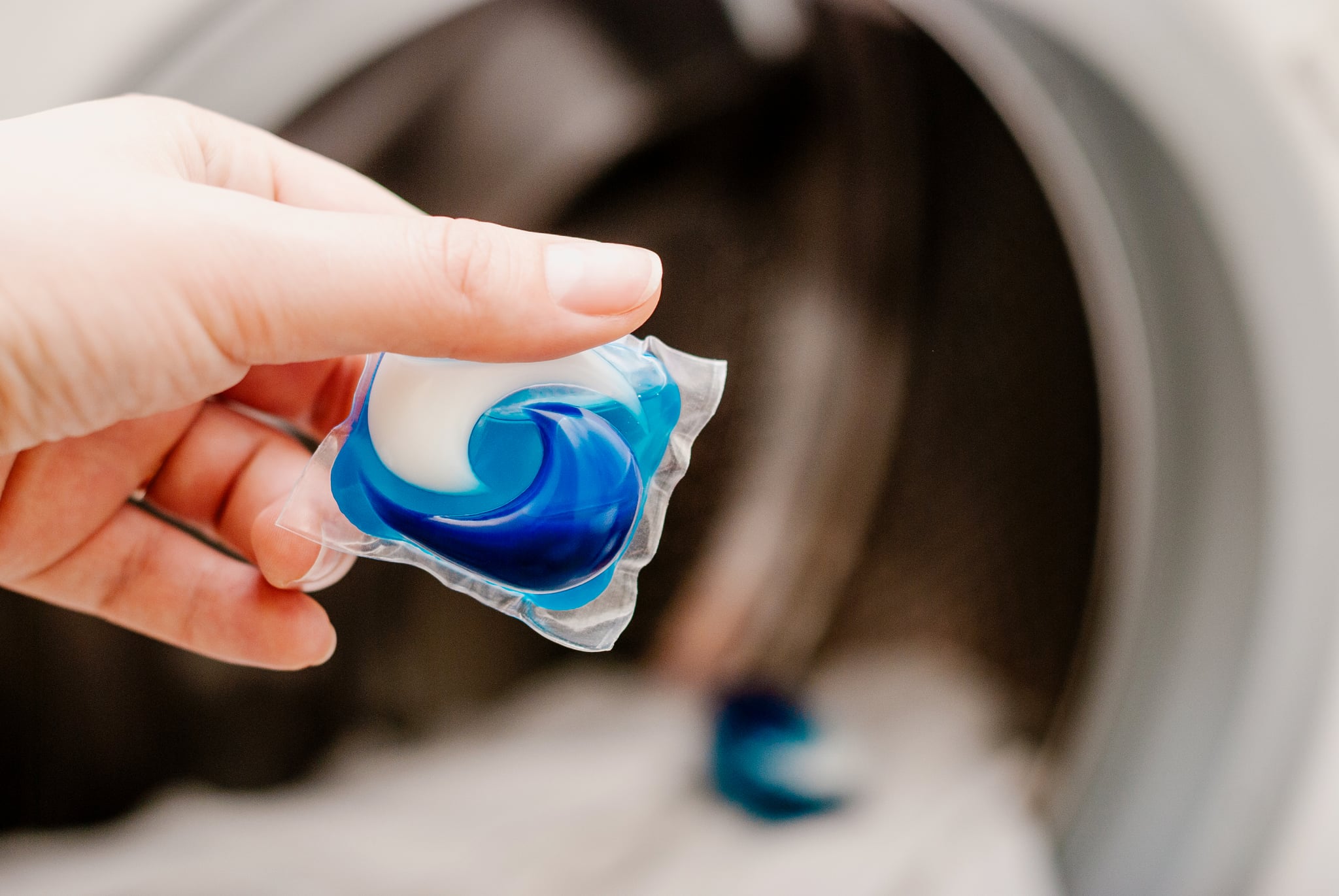 blue gel caps in hand for washing mashine, liquid coloured detergent