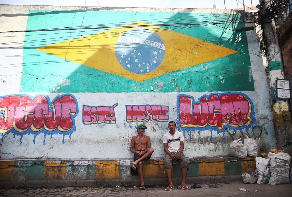 People sat beneath a painted flag in Rio de Janeiro.