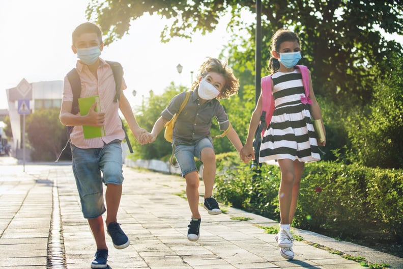 School during COVID- 19. Three happy children with backpacks wearing face protective masks. Coronavirus epidemic. New normal.