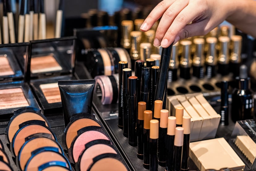 A woman chooses from various shades of makeup at a beauty counter.