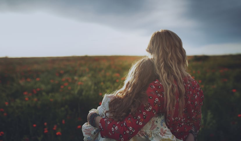 Mother and daughter hugging in poppy field